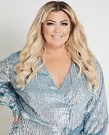 Woman with blonde hair wearing a blue sequin dress smiling