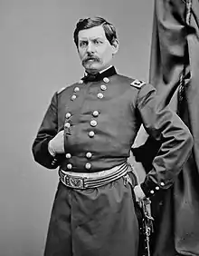 Photo of man with goatee and his right hand thrust into a dark military uniform