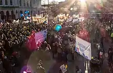 Protesters gathered in a square holding banners and Earth-coloured balloons.