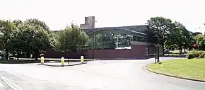 A swimming pool and gym complex behind a road and trees