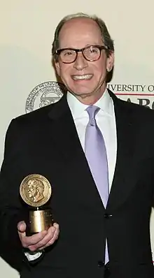 A waist-up shot of Harry Friedman holding an award