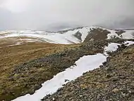 The prospecting trench on the summit of Hart Side, partly filled with snow, with Green Side and Stybarrow Dodd in the distance