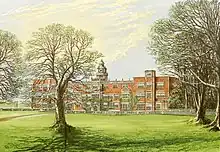 A large red-brick country manor house with trees in the foreground