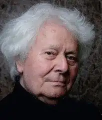 Dramatic portrait of clean-shaven old man with cloud of white hair, lit up against dark background