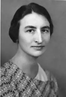 Black and white image of a woman with dark hair wearing a printed striped dress.