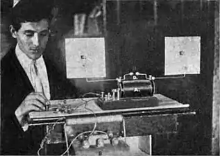 Hertzian spark oscillator, 1902. Visible are antenna consisting of 2 wires ending in metal plates (E), spark gap (D), induction coil (A), auto battery (B), and telegraph key (C).