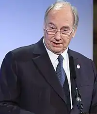 The Aga Khan giving a speech into a microphone