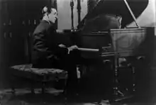 A man seated at a piano with his hands on the keyboard.