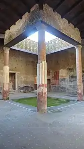 Same, but with a reconstructed roof. The lack of plaster shows how four horizontal beams, running between the four columns, support a short masonry wall (opus incertum), which in turn supports the rafters