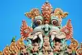 Thiruvanaikaval Kirtimukha top of gopuram with a ring-necked parakeet sitting next to it