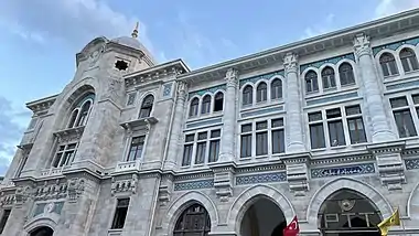 An arched neoclassical building with hanging PTT banners