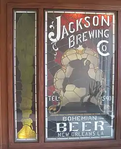 Stained glass panel with the silhouette of a man on a rearing horse and lettering for "Jackson Brewing Co."