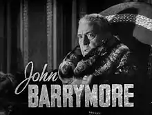 Publicity shot of a noticeably older, heavier Barrymore, wearing a fur coat; side on, facing slightly to his left