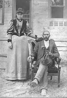 Black and white photo of a Black couple sitting on a porch.