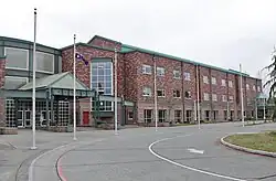 A three-story brick building with a driveway and several flagpoles