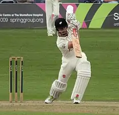 A man playing a shot wearing New Zealand Test jersey