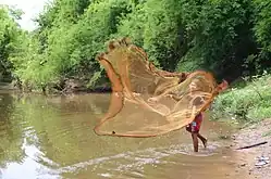 Boy casting from a riverbank