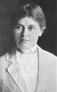 A black-and-white photograph of a white woman, Katrina Hertzer, with a serious expression, wearing a light-colored tailored suit and shirt, from a 1921 publication.