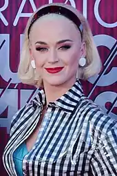 A woman with short blond hair and bright red lips stairs towards the camera