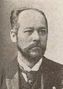 Sepia-toned image of a man with a beard wearing a suit and tie