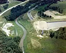 A stream flowing through a rural area of woods and fields with a dug channel to the right