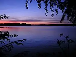 A lake surrounded by trees at sunset