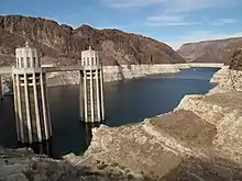 View of a reservoir where the water level has dropped, showing white deposits on the surrounding mountains