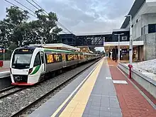 Electric multiple unit train stopped at the station platform, viewed from the end of the train facing the rest of the station