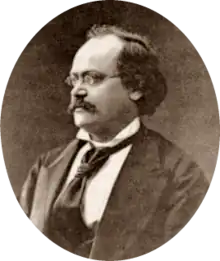 photograph of middle-aged white man with receding dark hair, spectacles and moustache, in semi-profile, facing right