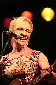 A woman sings and performs with a guitar