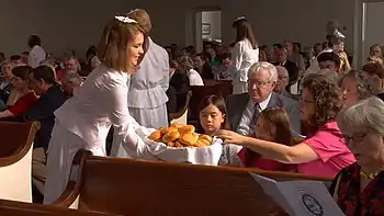 A Moravian diener serves bread to fellow members of her congregation during the celebration of a lovefest (2015).