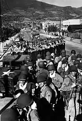 Men in trucks and military uniforms park in a town