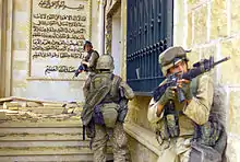 Color photograph of three U.S. marines entering a partially destroyed palace