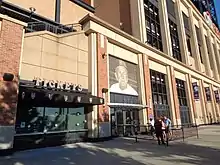 Exterior of a stadium. The admission gate has a large picture of Stengel in a Mets cap over it.