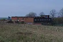 Red brick military building shown from the corner set in a field