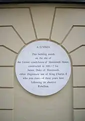  A white plaque on a beige wall noting where Monmouth House stood in Soho Square