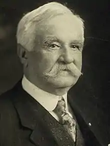 Elderly man with prominent mustache.