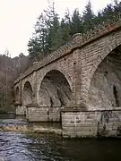 Close-up of a pier in the river, from which spring two skew arches