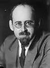 A man in a grey suit, light shirt and dark tie