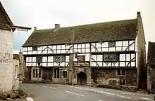 White fronted building with black beams prominent. Over the door is a sign saying The George Inn, Wadworths.