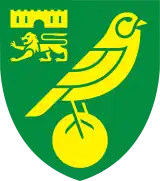 Badge of Norwich City: a green shield with yellow emblems. A bird (canary) on top of a ball as the main image, and a castle above a lion passant guardant in the top left quarter.