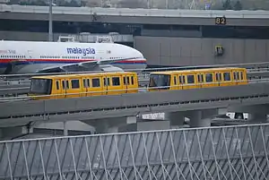 The Narita Airport Terminal 2 Shuttle System in March 2008 with a Malaysian airline aircraft behind