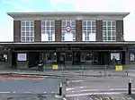 A brown-bricked building with a rectangular, black sign reading "OAKWOOD STATION" in white letters all under a light blue sky