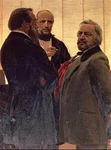 Three men standing together – two men with beards, the one on the right with grey hair, flanking a third man watching them intently