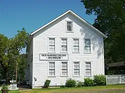 Photograph of the ox barn, a two-and-a-half story, whitewashed, wooden building of rectangular plan