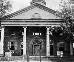 Black and white photograph of a brick neoclassical courthouse with a portico