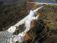 The image shows the Oroville Dam failing in February 2017.