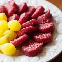 Dutch Amsterdamse uitjes (at left): small onions pickled with spices; the yellow colour is from either turmeric or saffron. Here served with ossenworst (smoked minced beef).