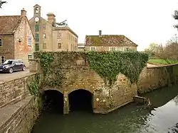 Two culverts opening into a river. In the background are industrial and residential stone buildings