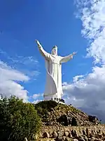 A white statue of Jesus with a bright blue sky in the background